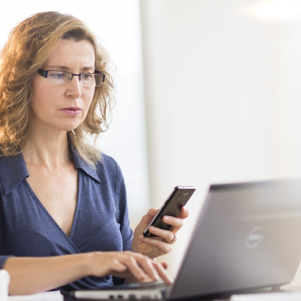 Businesswoman using laptop and phone